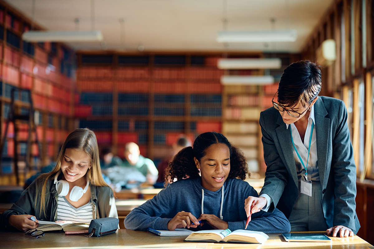 Teacher assisting students in library study session