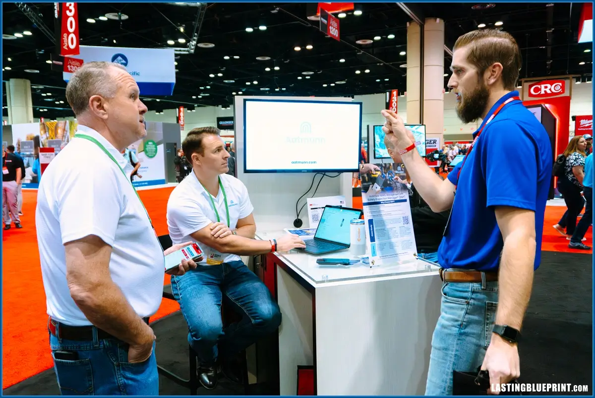 Three men talking at a trade show booth.