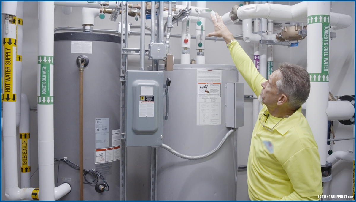 Owner training is led by an ouc vendor technician in a utility room with tanks and labeled piping — captured by orlando training video production company, lasting blueprint.